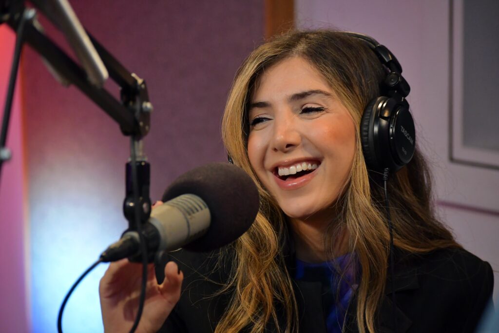 a smiling woman wearing headphones in front of a microphone